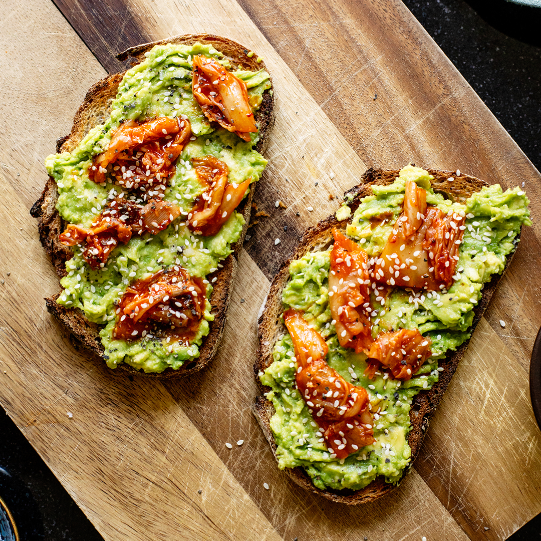 Kimchi Avocado Toast with creamy avocado, bibigo kimchi, and crispy sourdough bread, a flavorful fusion of ingredients.